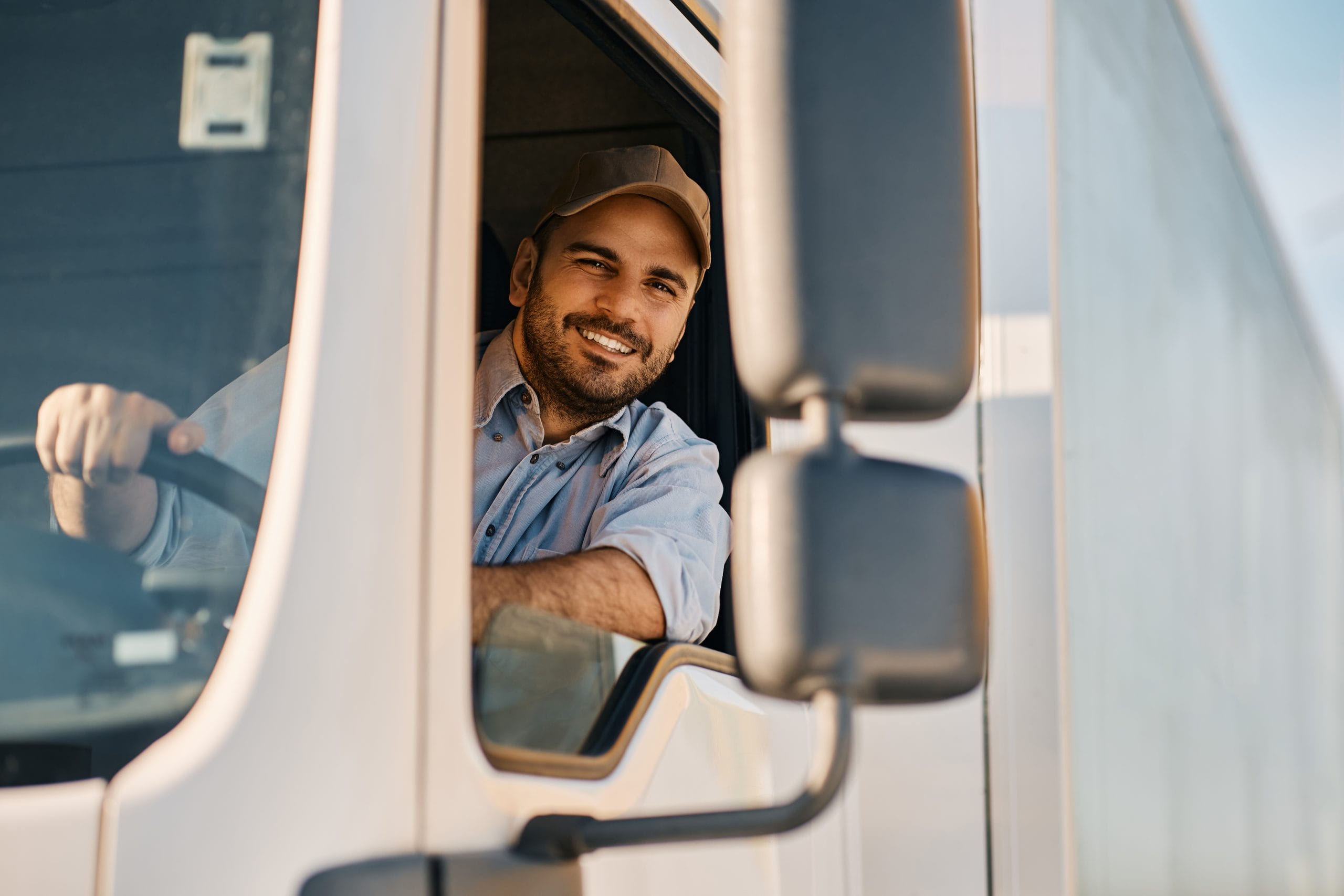 happy truck driver looking through side window while driving his truck.
